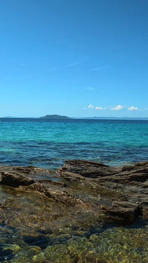 Tiny waves ripple around stone surfaces gently. Lagomandra, Greece. Vertical Stock Footage 339626313