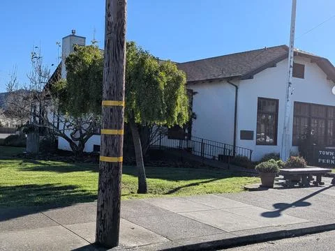 Tiny white building with bench, trees, and green grass Stock Photos