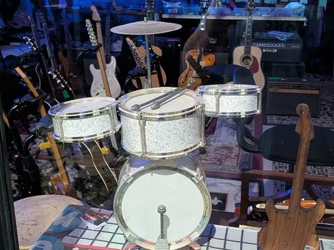 Tiny white drum set with three drums and foot drum in a music shop Photos