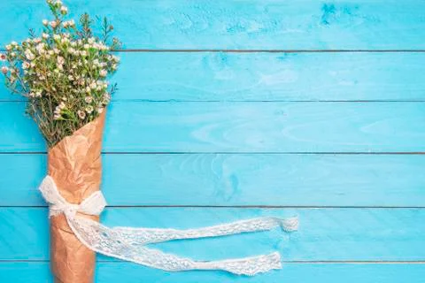 Tiny white flowers in a bouquet on a blue table. Above view of spring flowers Stock Photos