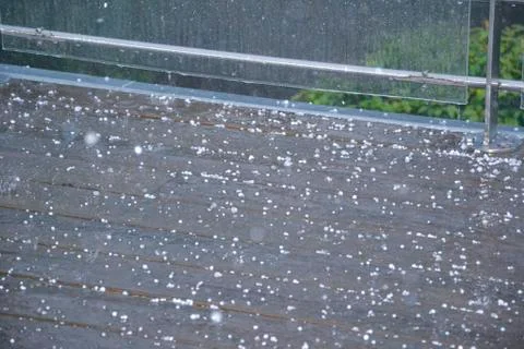 Tiny white grains of hail and rainwater cover the brown tiled balcony. Detail Stock Photos