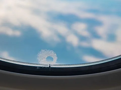Tiny window hole with ice crystal, A small bleed hole on airplane window. Stock Photos