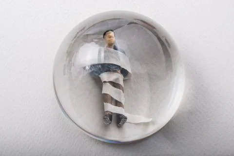Tiny wrapped figurine of man model  under magnifying glass 스톡 사진