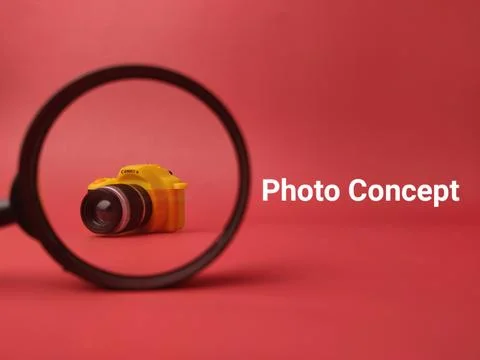 A tiny yellow camera is positioned inside a magnifying glass frame against .. 库存照片