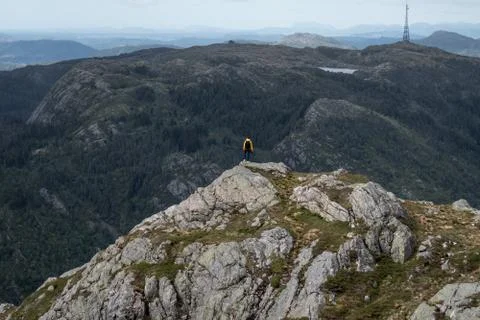 Tiny yellow person looking out on mountains Stock Photos