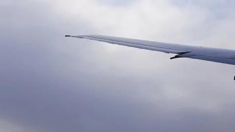 Tip of airplane wing with flaps moving in the wind and clouds in the air Stock Footage 171686899