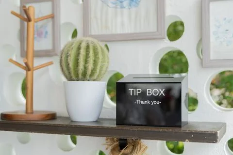 A tip box and flowers in a pot on the counter in the restaurant Stock Photos