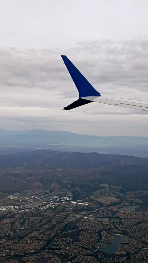Tip of the plane and city below mountains in the distance Stock Footage 317893572