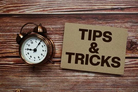 Tips And Tricks text with alarm clock on wooden background Stock Photos