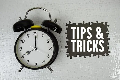 Tips And Tricks text with alarm clock on gray background Stock Photos