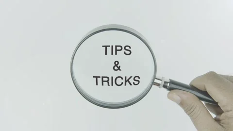 Tips And Tricks text or word highlighted by a magnifying glass in a hand Stock Footage 303726868