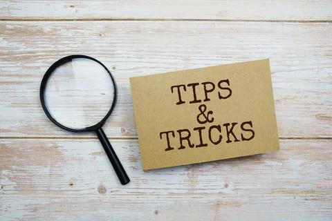 Tips &amp; Tricks text message and magnifying glass with space copy on wooden b.. Stock Photos