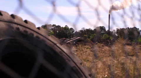 Tire and chimney stack through fence 库存影片 39566286