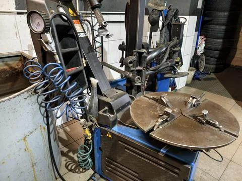 A tire changing machine is placed in a garage. Various tools are visible, ind Photos