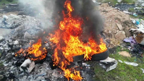 A tire is on fire in a pile of trash Видео 314390024