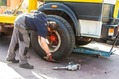 Tire repairer at work that changes and repairs truck and car tires in the garage Stock Photos