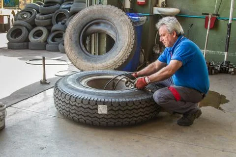 Tire repairer at work that changes and repairs truck and car tires in the garage Stock Photos