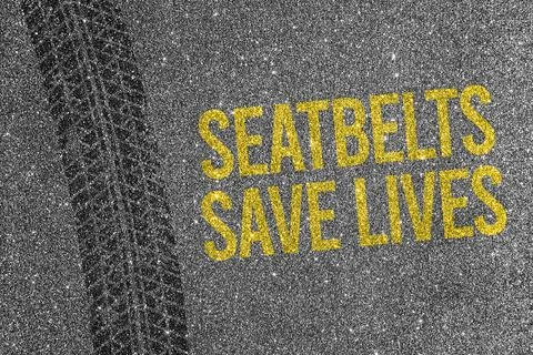Tire track on asphalt background with yellow text Seatbelts Save Lives. Roa.. Stock Photos