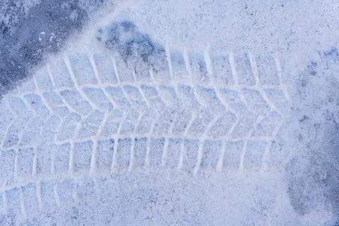 Tire tracks on a snowy surface indicate movement and travel. The pattern Stock Photos