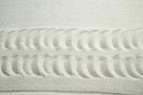 Tire tread pattern imprinted in fine light-colored sand, creating a texture.. Stock Photos