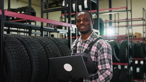 Tire warehouse worker managing inventory with a laptop Stock Footage 301557568
