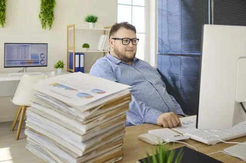 Tired accountant man at computer in office, facing deadlines and paperwork Stock Photos