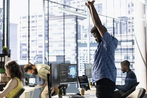 Tired admin stretching limbs while using computer for artificial intelligence Stock Photos