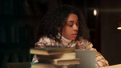 Tired African American student studying behind pile of books in library Stock Footage 322902145