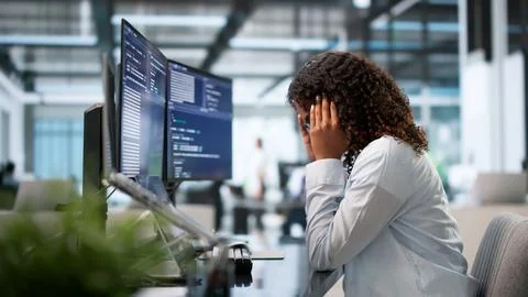 Tired African Female Coder Struggles With Headache While Debugging Code Late. Foto stock
