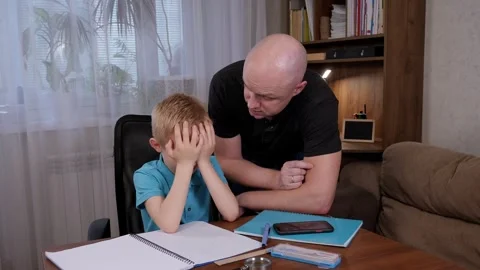 A tired and angry father does homework with his son while sitting at his desk. Stock Footage 305293521