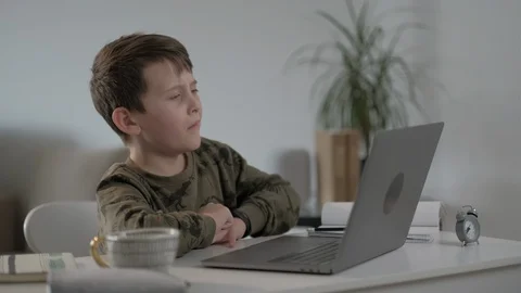 Tired and sleepy child doing homework using laptop typing  notes at home. Stock Footage 128391007