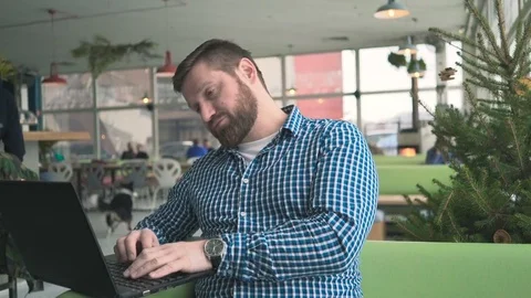 Tired and sleepy man browsing laptop in cafe, portrait, steadicam shot  Vídeo Stock 72951623