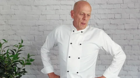 A tired and stressed chef takes a break from the kitchen. The male sighs 스톡 동영상 179336012