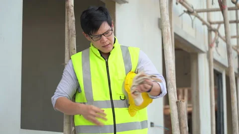 Tired asian foreman take a break and taking off gloves  outdoors on construct Stock Footage 146445487