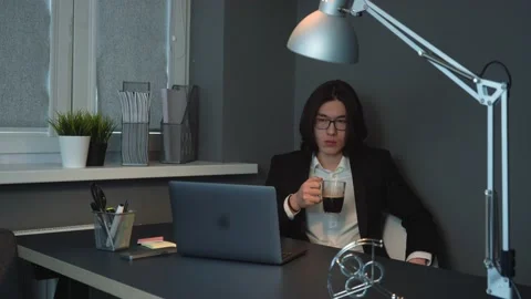 Tired Asian Man Seating at Work Drinking Coffee Thinking How to Manage to Work Stock Footage 148365412