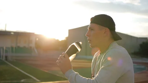 The tired athlete with baseball cap drinks water from the bottle on stadium 스톡 동영상 64021338