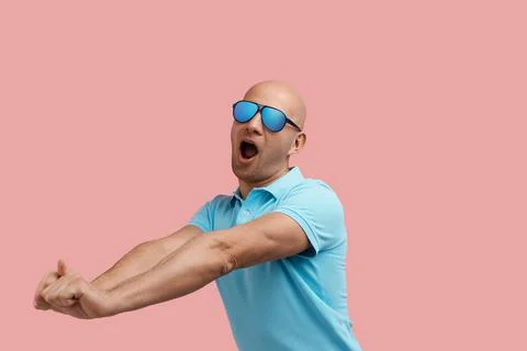 Tired bald homosexual man with bristle is yawning and stretching after workou Stock Photos