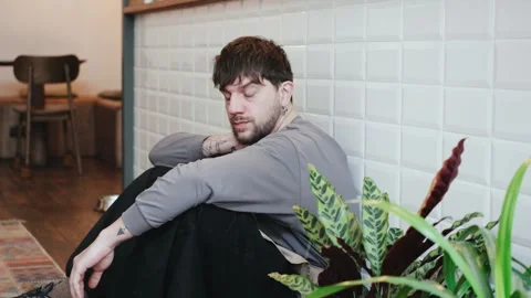 Tired barista takes a break while sitting on the floor in a cafe, showing a Stock Footage 330976762