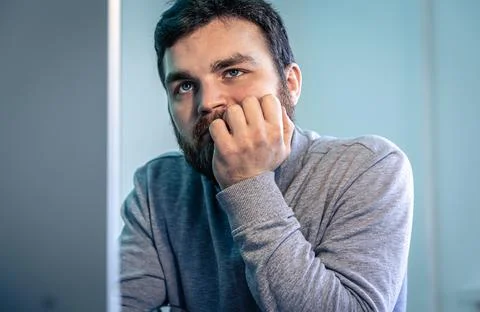 Tired bearded man looks at the computer screen. 스톡 사진