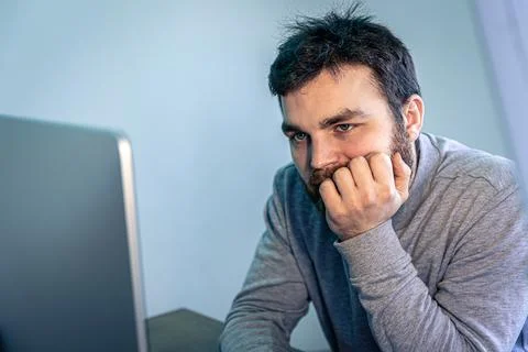 Tired bearded man looks at the computer screen. 스톡 사진