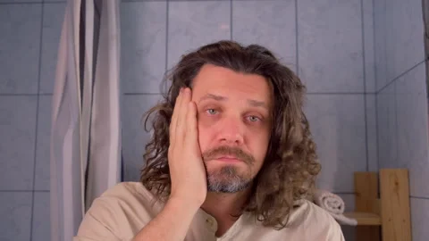 Tired bearded man touching face in bathroom shocked his appearance in mirror. Stock Footage 309012351