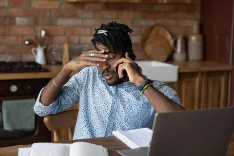Tired black man freelancer engaged in multitask feel information overload Stock Photos