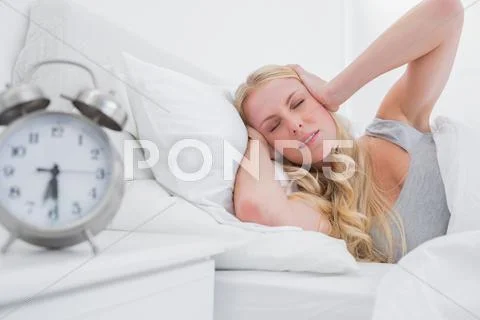 Tired blonde woman covering ears with hands Stock Photos