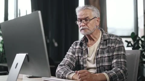 Tired boring gray haired senior man freelancer feeling annoyed at workplace Sad Stock Footage 253513279