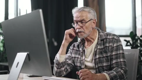 Tired boring gray haired senior man freelancer feeling annoyed at workplace Sad Stock Footage 253513599