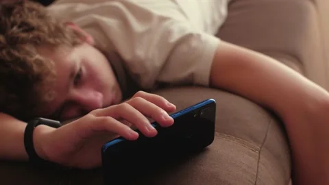 Tired boy playing phone Видео 158166916