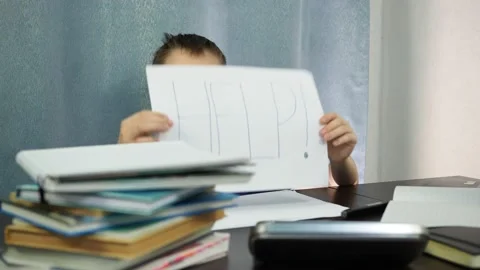 A tired boy sitting at a table shows a sign that says help. studying at home is Stock Footage 145276381