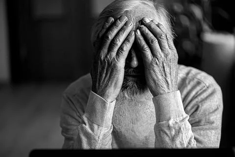 A tired, broken, resigned, preoccupied elderly man sits in front of a laptop, Stock Photos