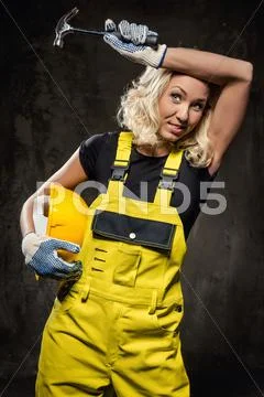 Tired builder woman with hammer and helmet indoors Stock Photos