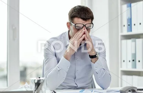 Tired businessman with eyeglasses in office Stock Photos